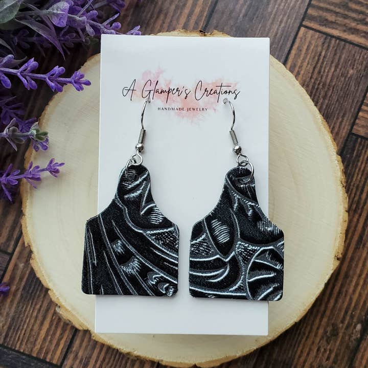 Zwarte en zilveren leren oorbellen met westernbloemen en koeienlabel voor wholesale door A Glamper's Creations LLC