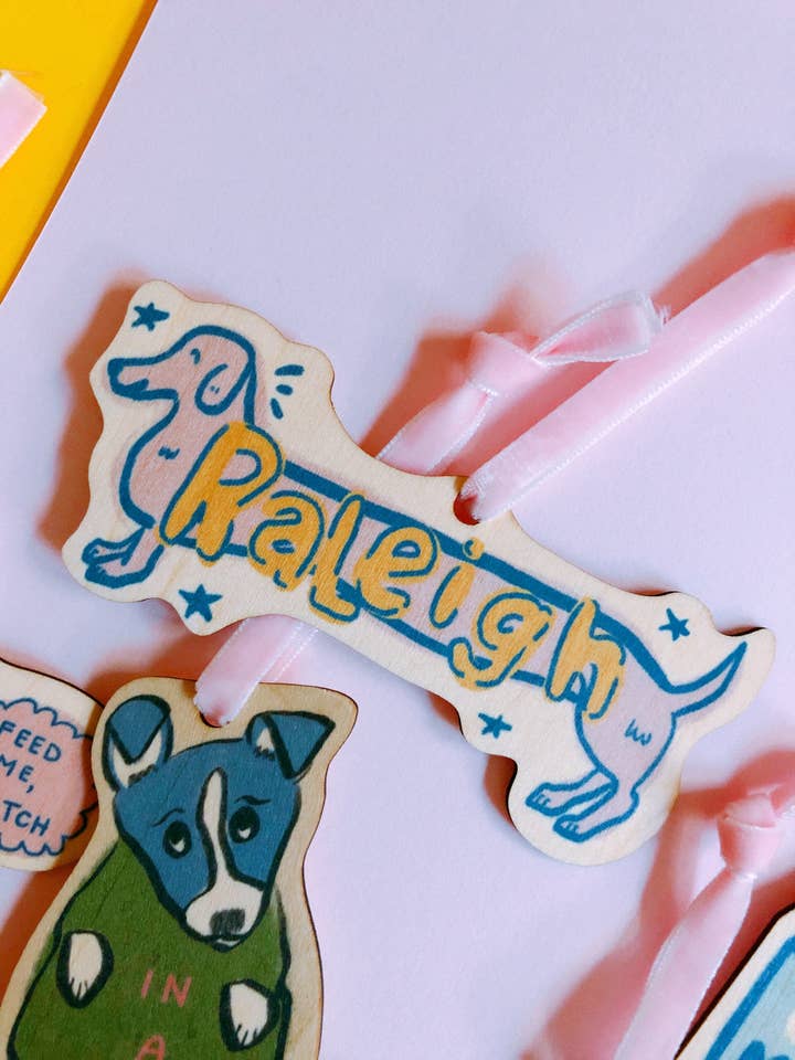 Simpatico ornamento natalizio in legno colorato unico per cani Raleigh per la vendita all'ingrosso da parte di Emily Petrilla Illustrations