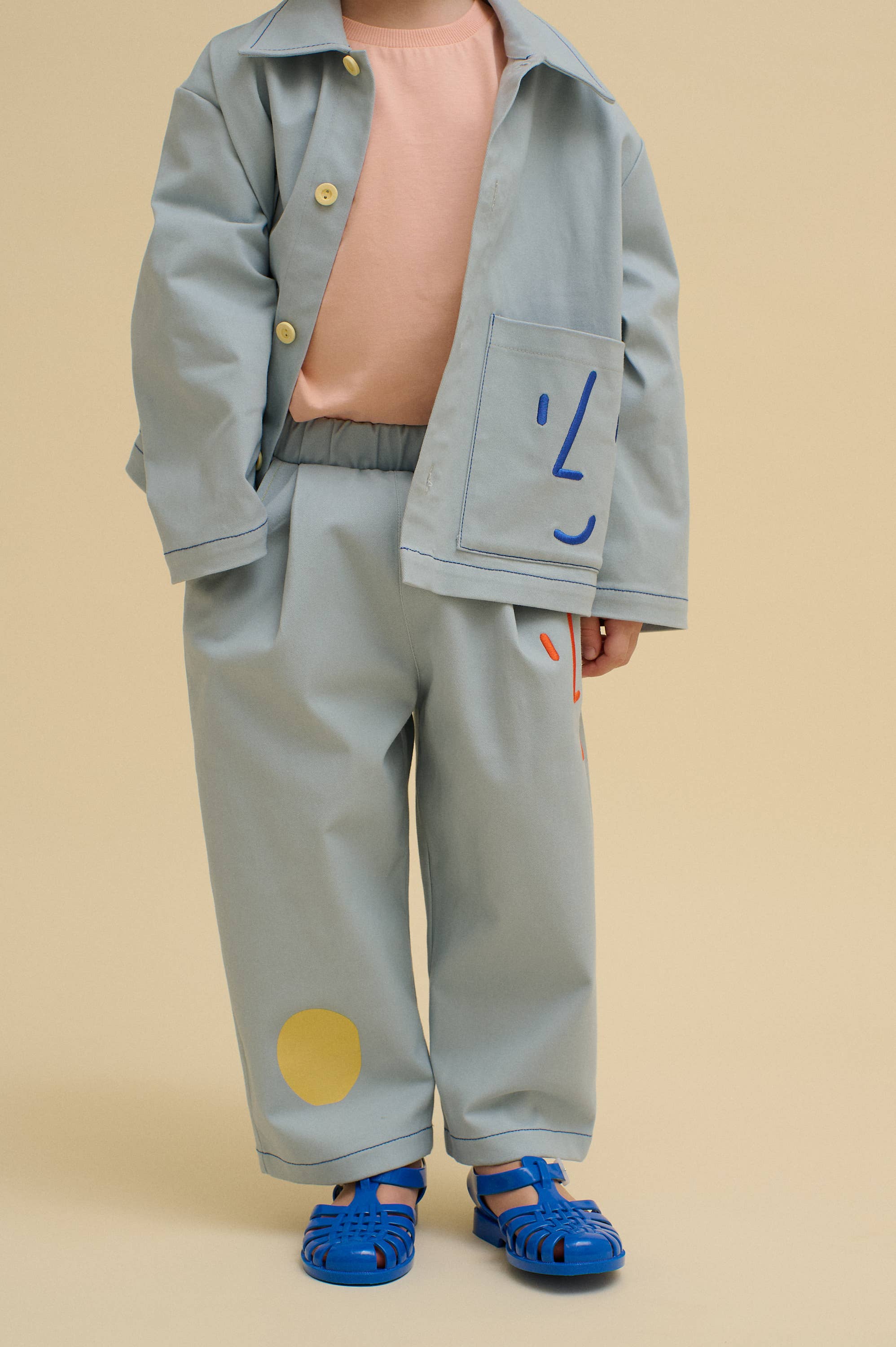 Blauw Utility jas met speelse geborduurde gezichten voor groothandel op Faire2