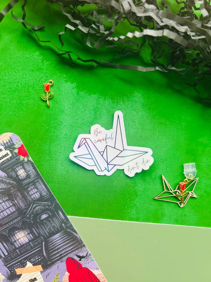 Alchemised/dramione crane ‘be careful don’t die’ Inspired Holographic Sticker – Fantasy Bookish Laptop & Kindle Decal for wholesale by TheBookShack