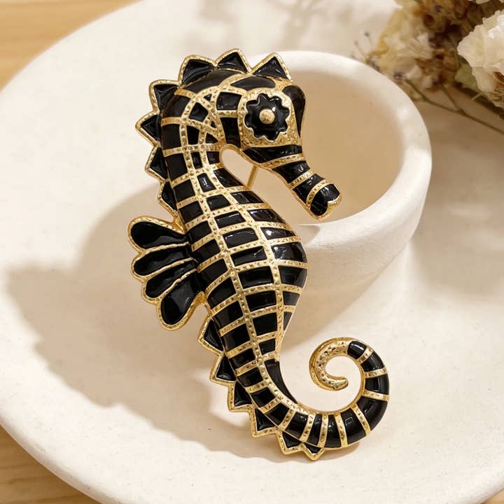 Guldfärgad sjöhästformad brosch med svart emalj för wholesale av IngrossoZagatto by INCI SRL