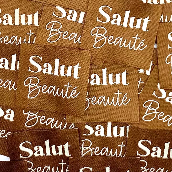 "Sew-on woven label 'HELLO BEAUTY' Camel" for wholesale by L’Étiquette Home Couture