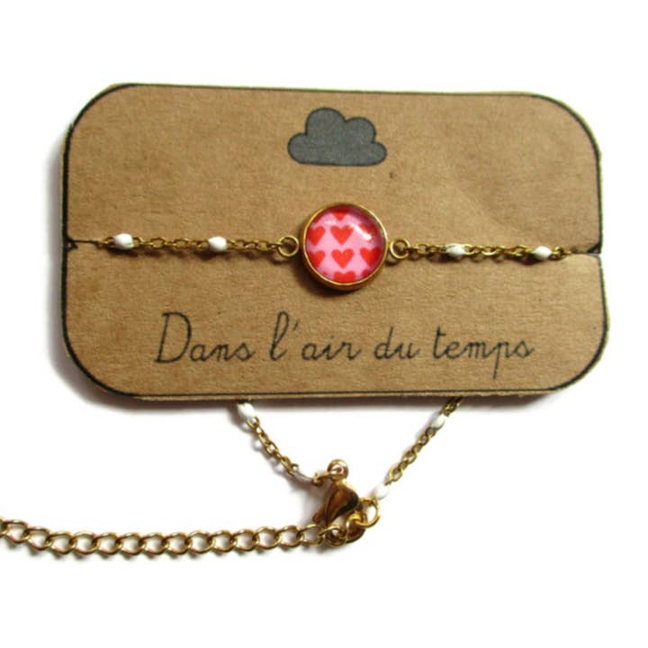 Dans l'Air du Temps Bijoux – wholesale Berlockarmband – Rött hjärtarmband med guldfinish eller silverfinish på rosa bakgrund2