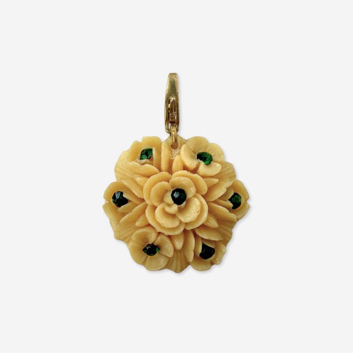 Vintage pale yellow carved celluloid flower charm with green rhinestones for wholesale by Lulu’s Petals