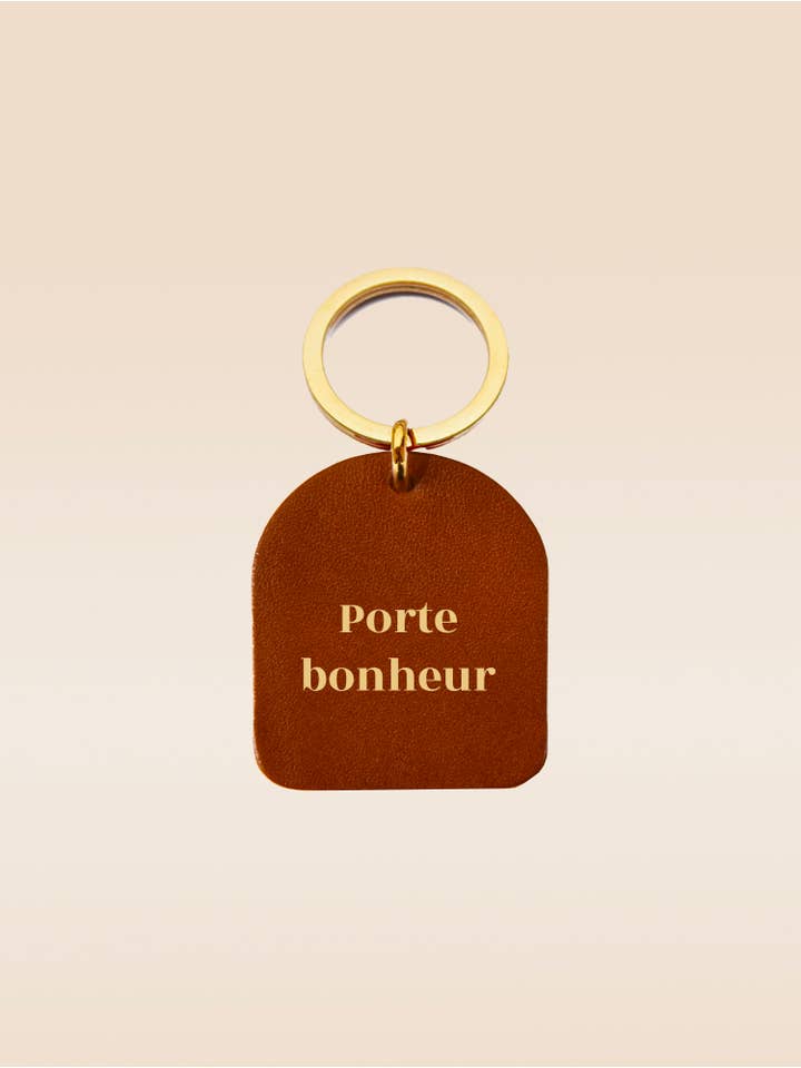 Geluksbrenger sleutelhanger van camelkleurig rundleer met boogvorm voor wholesale door FAUVETTE PARIS