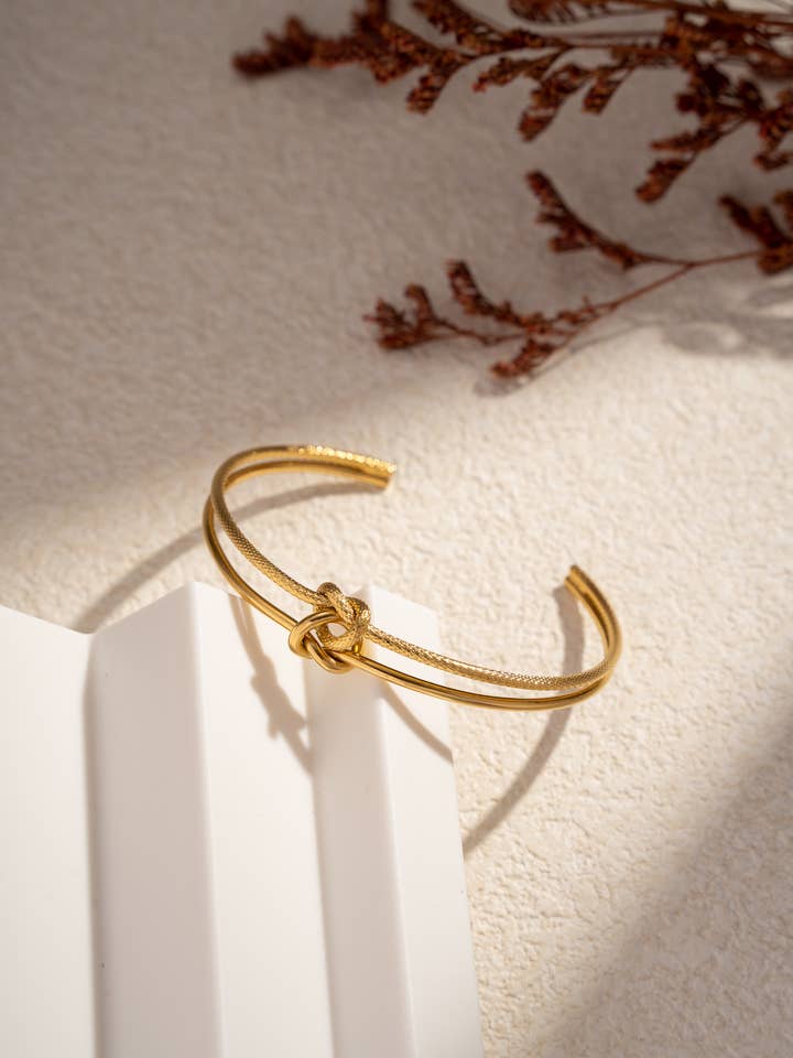 Minimalist gold bangle bracelet with refined central knot for wholesale by COSMOS