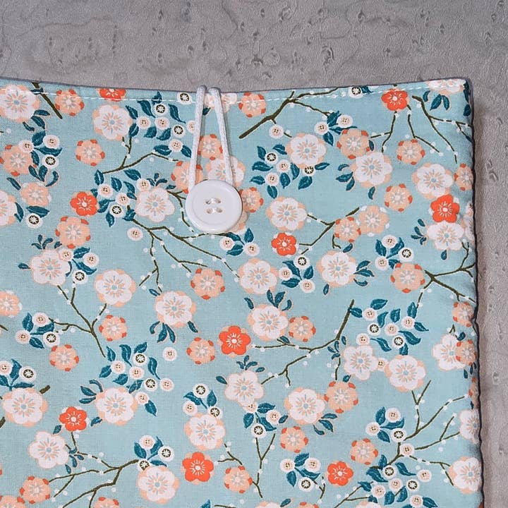 Polstret bogomslag med hvide blomster på lyseblå baggrund for engroshandel hos laubelgo