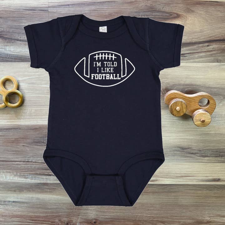 I'm Told I Like Football Silhouette Baby Bodysuit for wholesale by Rocket Bug
