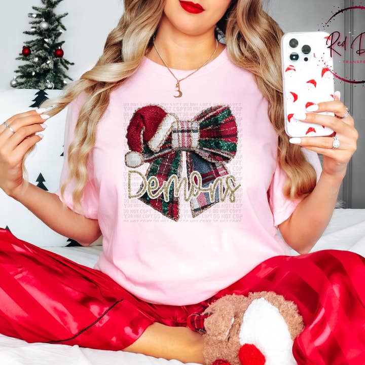 Demons Christmas Bow Mascot T-Shirt | Trendy School Spirit Shirt | Fast Shipping | Super Soft Shirts for Men/Women/Kid's for wholesale by Red Dirt Transfers