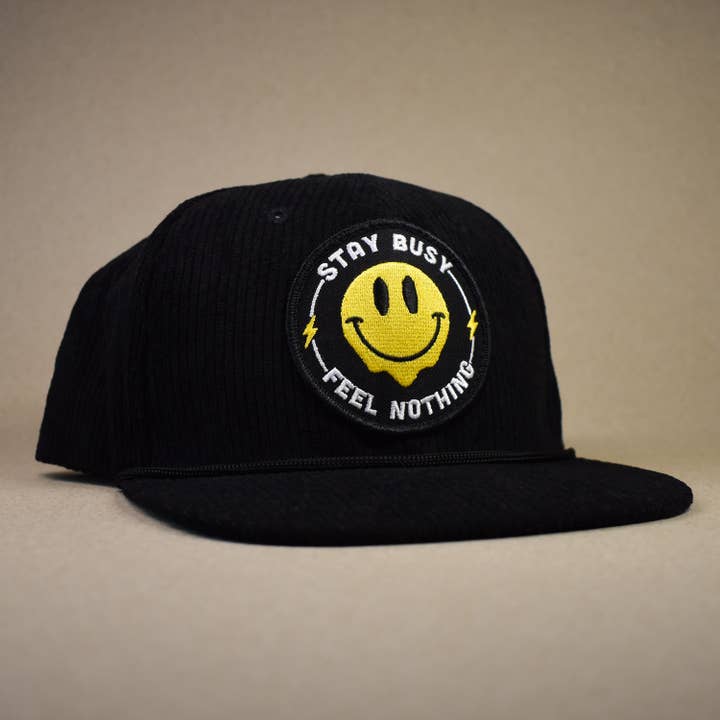 Cappello "Rimani Occupato, Non Sentire Nulla" per la vendita all'ingrosso da parte di Retrograde Supply Co.