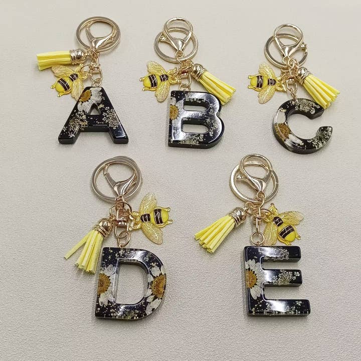 Nøglering med præssede tørrede blomster, harpiksinitialer og bi-vedhæng for engroshandel hos Mio Queena