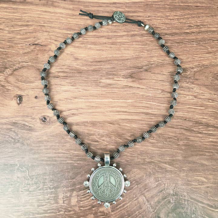 Collier avec pendentif pièce signe de paix en argent dans un sertissage perlé. pour la vente par ZINC Designs