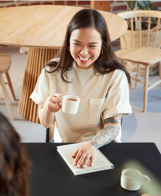 Person Smiling While Holding a Cup of Coffee