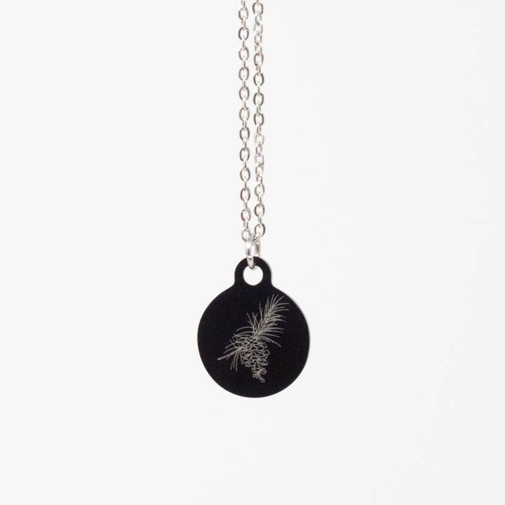 Collier en acier inoxydable noir pomme de pin illustrée pour la vente par Mama Peacock LLC