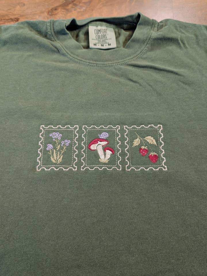 Geborduurd T-shirt met bloemen, paddenstoel, aardbei, slak en stempel. voor wholesale door Penelope Annen Design