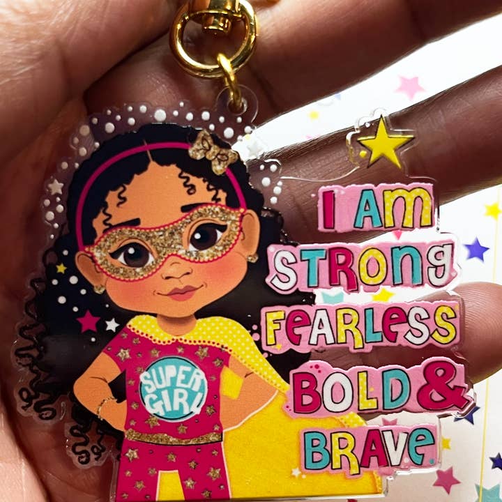 Braunes Mädchen Superhelden-Schlüsselanhänger – Ermächtigender recycelter Acryl-Taschenanhänger für Kinder | Afro-Mädchen-Schlüsselanhänger von Fefus Designs für den Großhandel von Fefus Designs