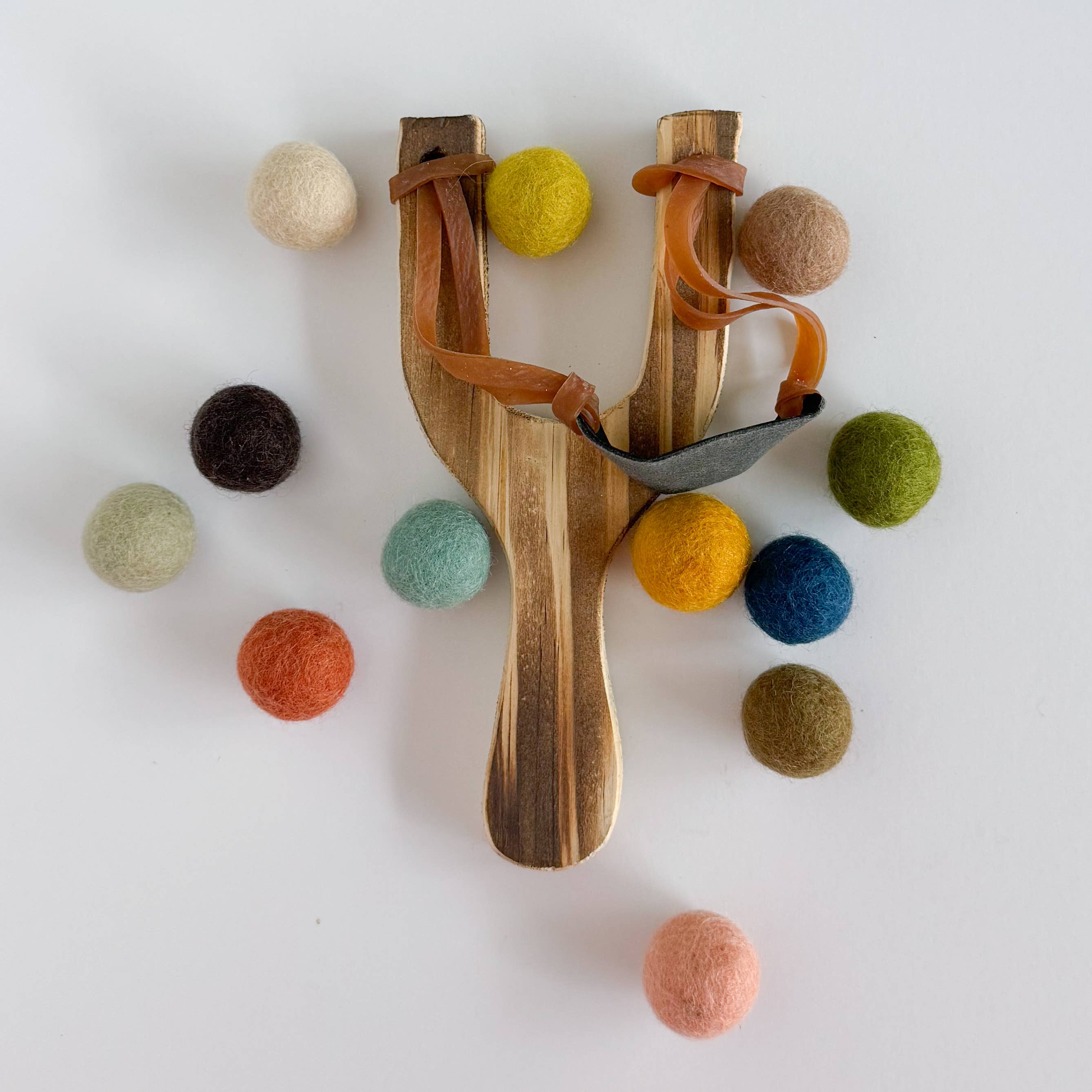 Muted Rainbow Wood Slingshot with 12 Felt Balls  for wholesale on Faire0