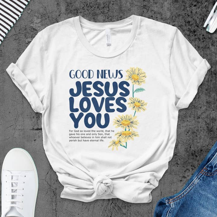 Kvinders inspirerende Jesus-T-shirt, gode nyheder Jesus elsker dig, blomsterkristen tee, bibelvers religiøst tøj, gaveide for engroshandel hos FreakyTeeFactory