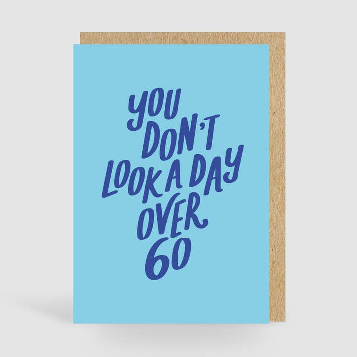 Non sembri un giorno con più di 60 anni! Biglietto di compleanno blu per la vendita all'ingrosso da parte di Jane Katherine Houghton Designs