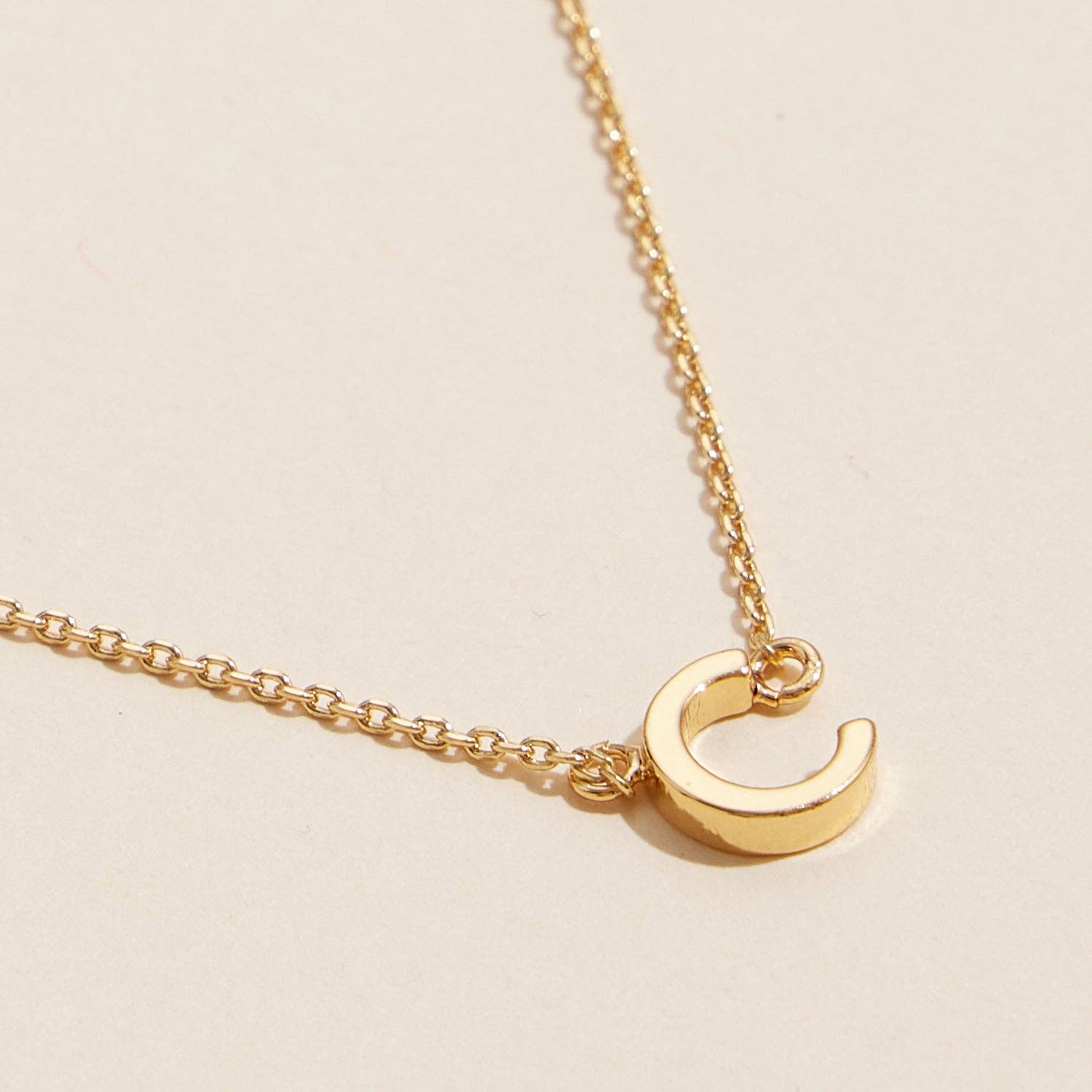 16 ACTIVOS Paquete de 16 collares dorados con abalorios metálicos con letras iniciales de venta al por mayor en Faire4