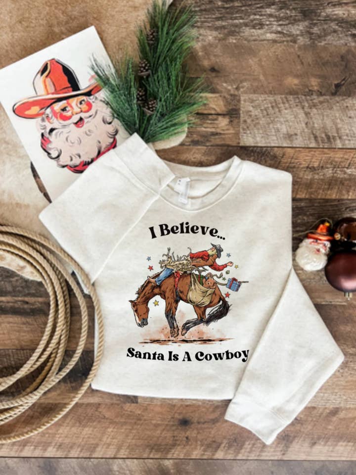 I Believe Santa Was a Cowboy Tee or Sweatshirt(Heath. Cream) for wholesale by The Fringed Pineapple