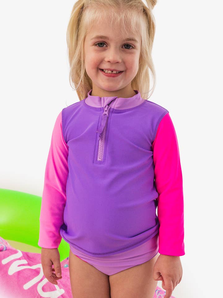 Girls Neon Purple Color Block Long Sleeve Zipper Rash Guard 2-Piece Swimsuit with Signature Rear Ruffles
for wholesale by RuffleButts + RuggedButts