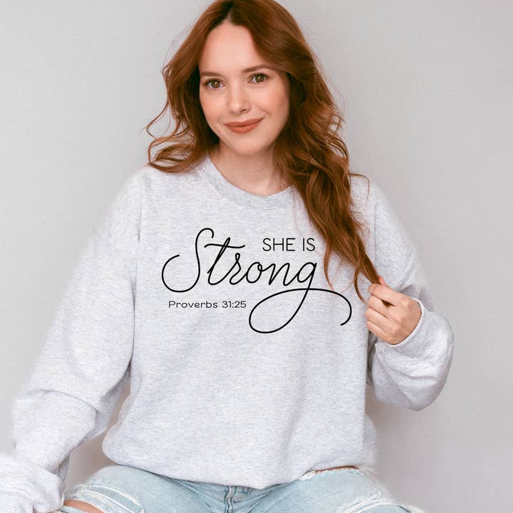 Sweatshirt graphique chrétien She Is Strong Proverbs 31 pour la vente par Words & Wellness