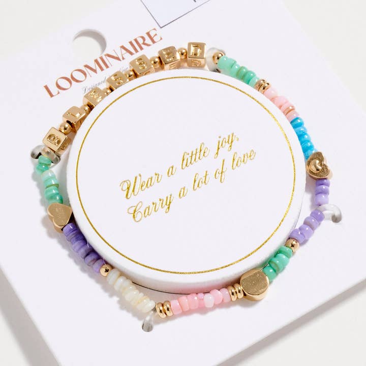 Bracciale elastico ispirazionale con perline placcate oro "Blessed" con cubetti di lettere dorate e accenti a forma di cuore. per la vendita all'ingrosso da parte di Frem