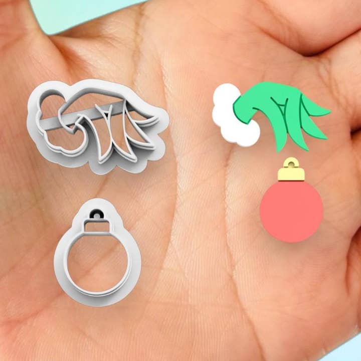 Emporte-pièce en forme de main du Grinch avec boule de Noël imprimé en 3D pour la vente par Roussell Prints and Demand LLC