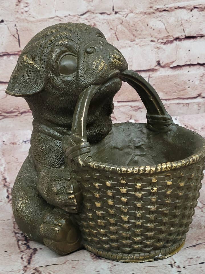 Bronze mops-hvalp, der holder flettet kurv – hundefigur for engroshandel hos Bronzhaus