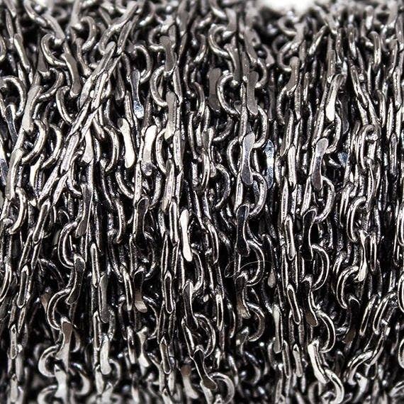 Chaîne à maillons ovales ouverte et fermée de 2 mm en métal doré noir à côté du pied pour la vente par The Bead Traders