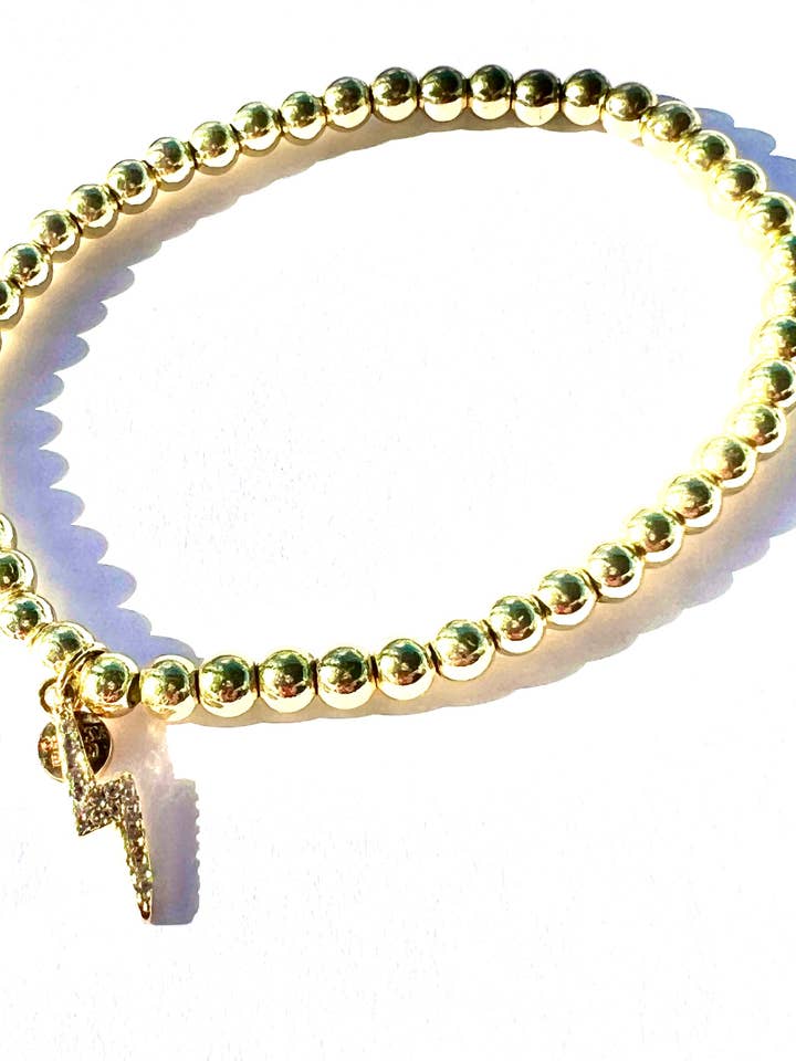 AMPED | Gold stretch bead bracelet with CZ bolt charm for wholesale by CHEEKYBOOM