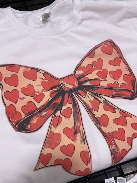 Par.tees by Party On! - Venta al por mayor Camiseta estampada - Unisex - Camiseta gráfica neutral con lazo y corazón rojo de San Valentín coqueta.1