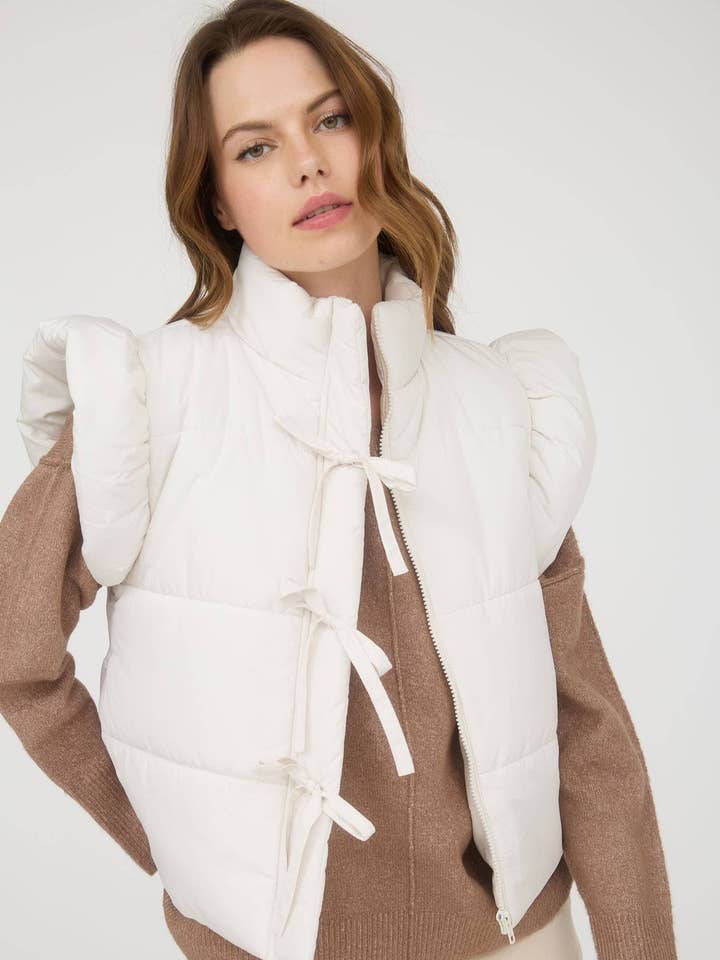 GILET MATELASSÉ À FERMETURE ÉCLAIR AVEC DÉTAIL NŒUD ET MANCHES VOLANTES pour la vente par MINE