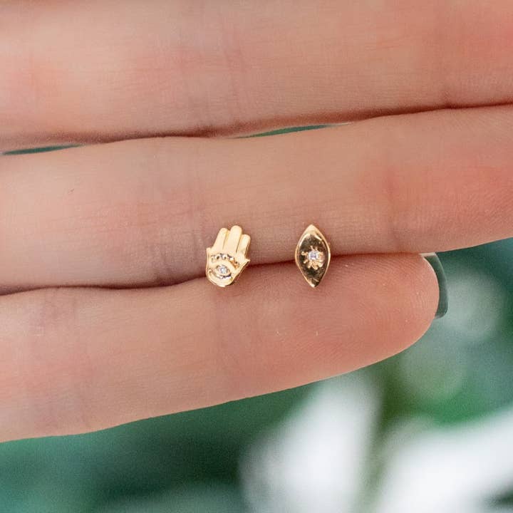 Asymmetrical Gold Evil Eye and Hamsa Stud Earrings för wholesale av The Curated Lobe
