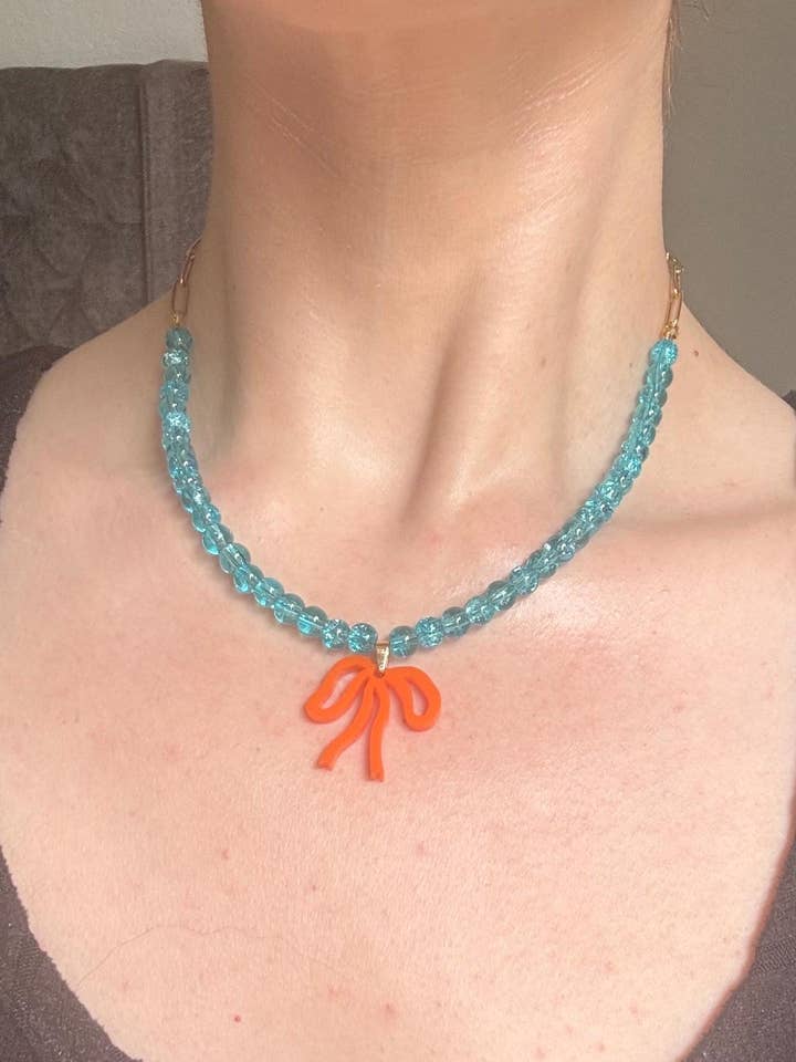 Collier à perles bleu ciel avec nœud orange – breloque nœud en acrylique faite à la main sur perles de verre bleu ciel | Bijoux cottagecore, whimsygoth et mode alternative pour la vente par Squishy Jewellery