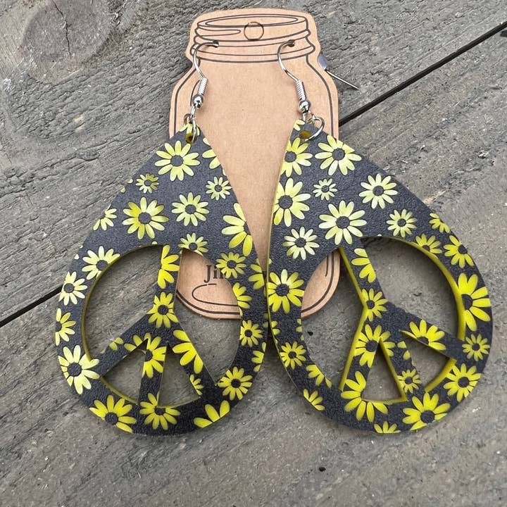 Orecchini in acrilico a forma di margherita gialla nera con simbolo della pace per la vendita all'ingrosso da parte di Jill's Jewels