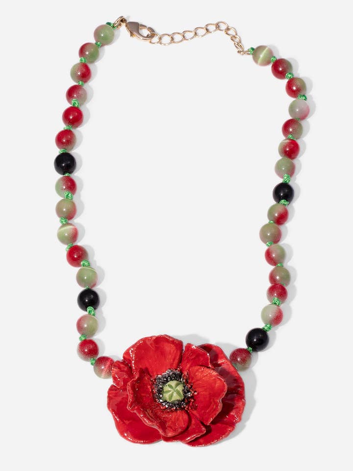 VALMUE-HALSKÆDE, KORT HALSKÆDE MED PERLER I JORDTONER MED KERAMIKSTYKKE I FORM AF EN VALMUE for engroshandel hos CASHFANA