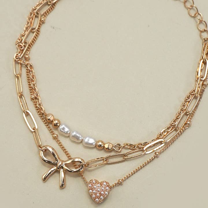 Gold CHARM BRACELET-MULTI LAYER BOW PERAL HEART CHARMS | 80B1317 for wholesale on Faire