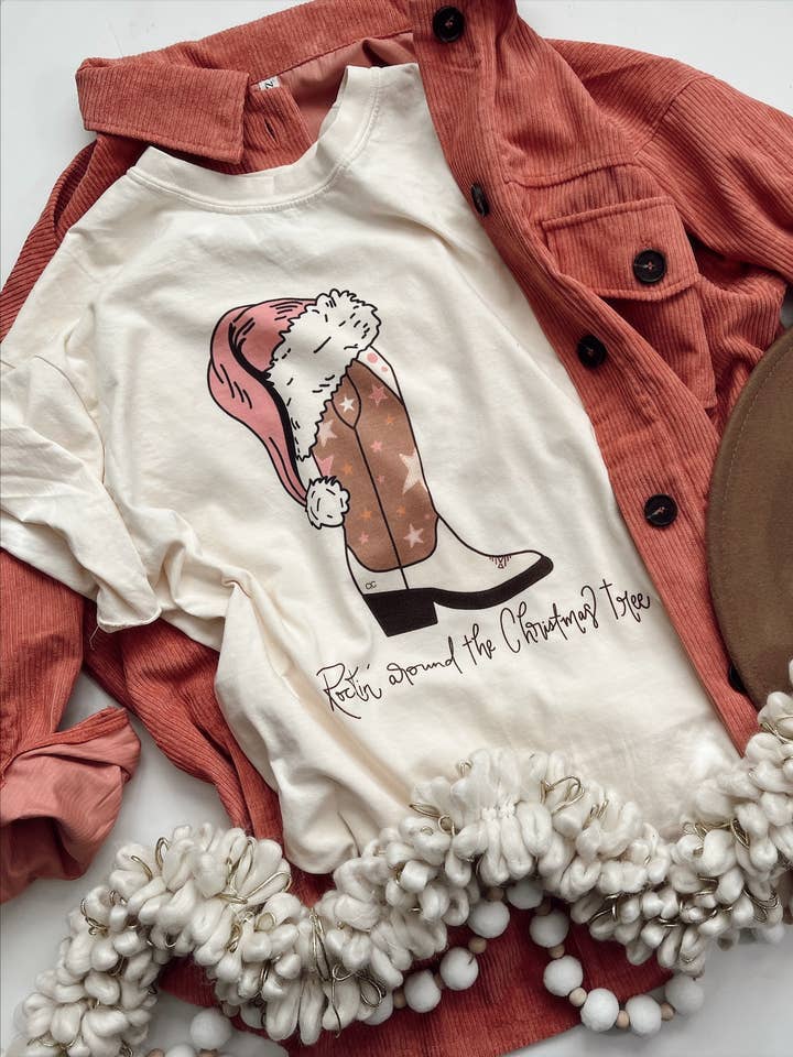 T-shirt grafica con stivali che dondolano intorno all'albero di Natale per la vendita all'ingrosso da parte di Whitney | Chaudoin Creations