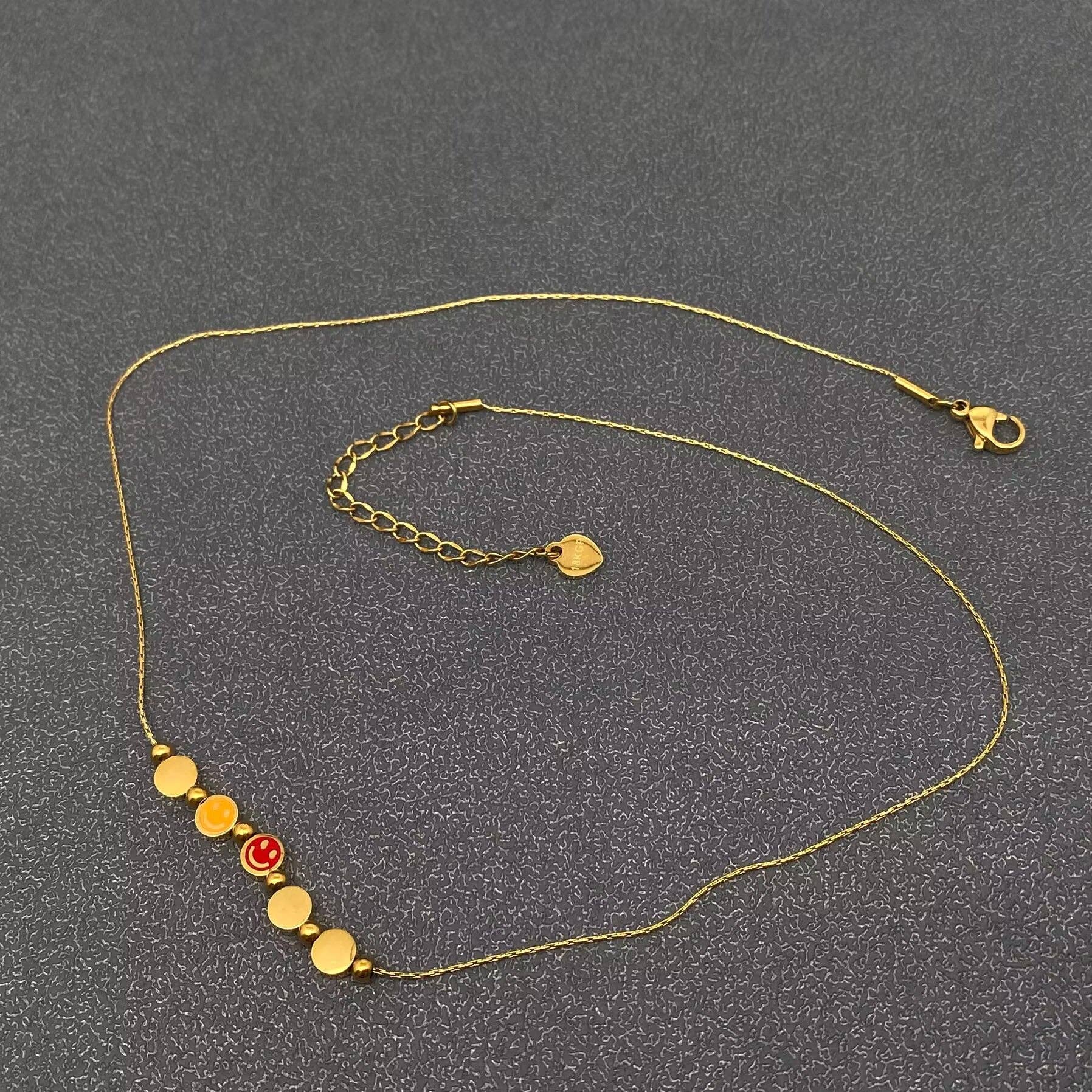 Mio Queena - Vente Colliers à pendentif - Collier en acier inoxydable plaqué or 18K avec 5 visages souriants en émail - FGS1