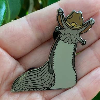 Slug wearing a cowboy hat hard enamel pin for wholesale by Thruhalia's Art