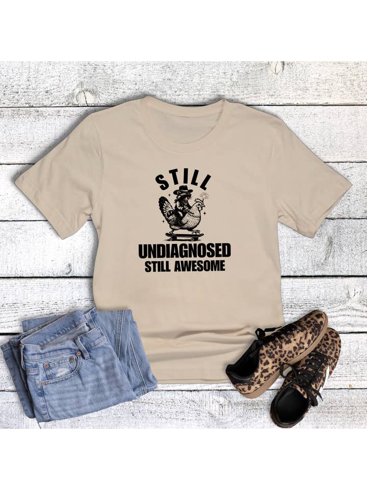 Cream Funny Still Undiagnosed Still Awesome Graphic Tee for wholesale on Faire