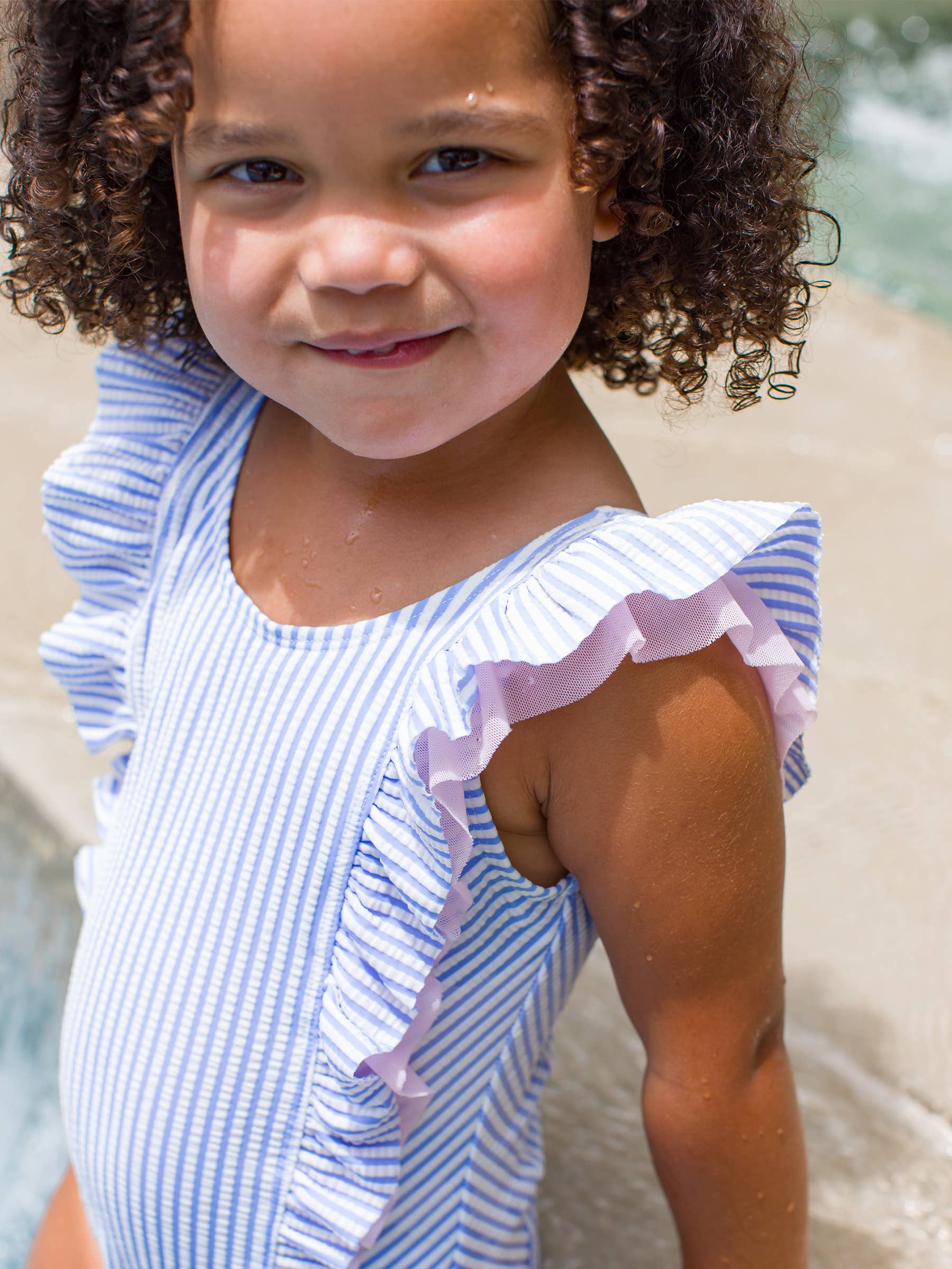 RuffleButts + RuggedButts – Engroshandel Badedragt - Børn – Pigernes periwinkleblå seersucker vandfaldsbadedragt i ét stykke6