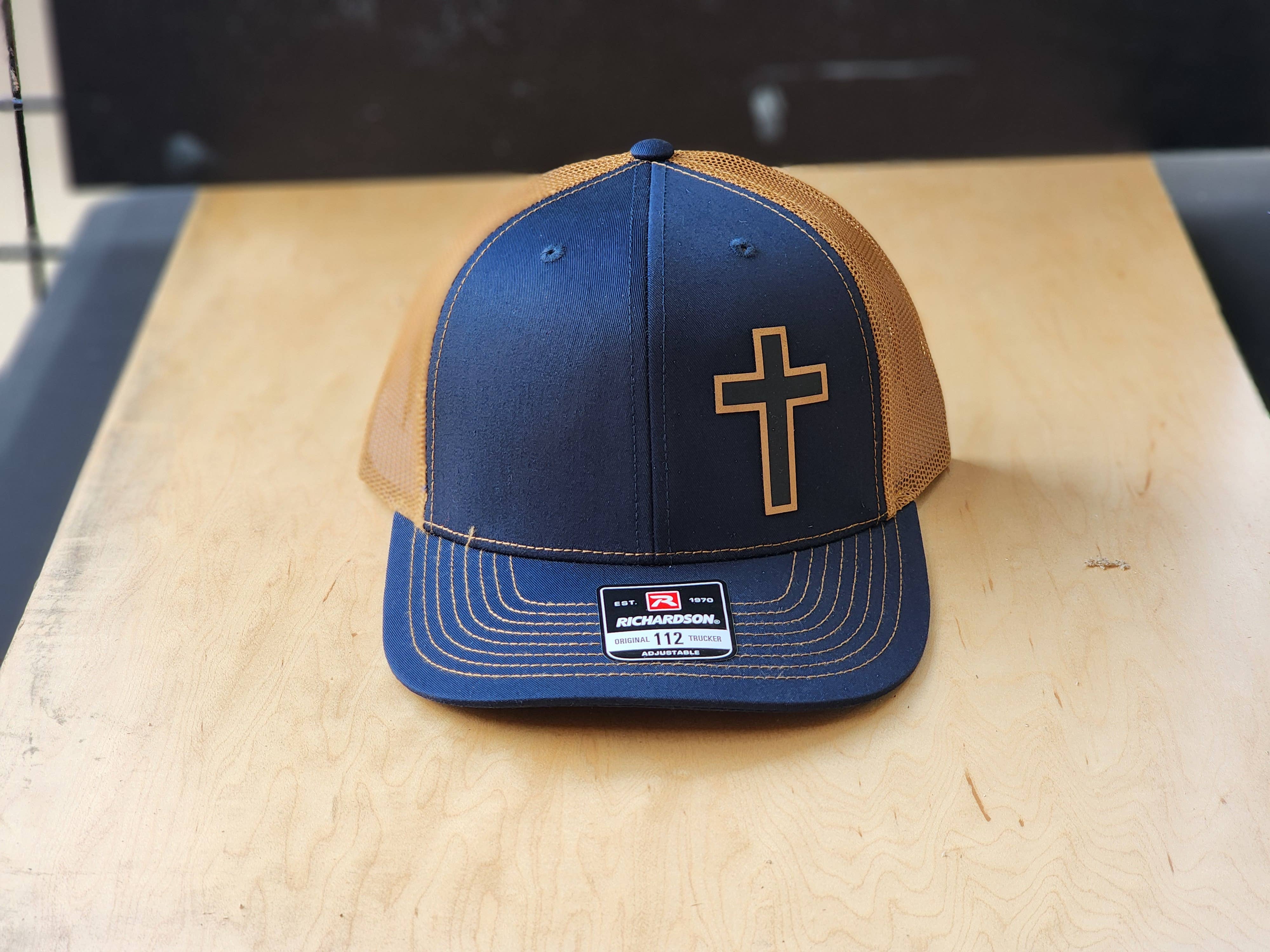 Knot Creatives – Großhandel Trucker-Cap – Unisex – Marineblaues Tan-Mesh-Trucker-Cap mit Kreuzdesign1