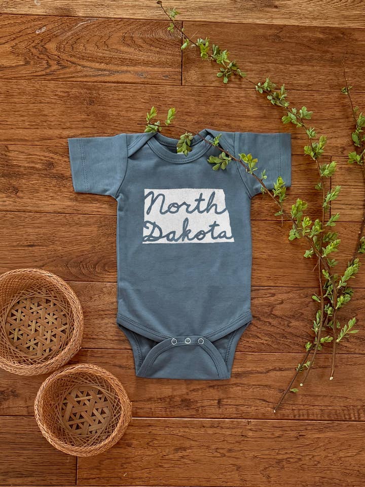 North Dakota Cursive, baby bodysuit, 100% Organic Cotton for wholesale by Birds Kept North