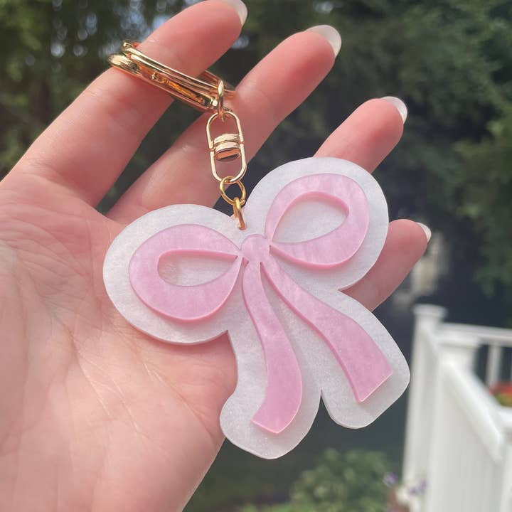 Pearlescent Pink and White Bow Keychain with Gold Features and other Purchase Wholesale bow keychain. Free Returns & Net 60 Terms on Faire trending on Faire.