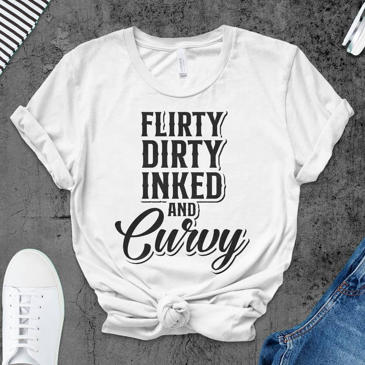 T-shirt Flirty Dirty Inked and Curvy, dichiarazione audace, regalo per amanti dei tatuaggi, abbigliamento taglie comode, maglia tipografica alla moda donna per la vendita all'ingrosso da parte di FreakyTeeFactory
