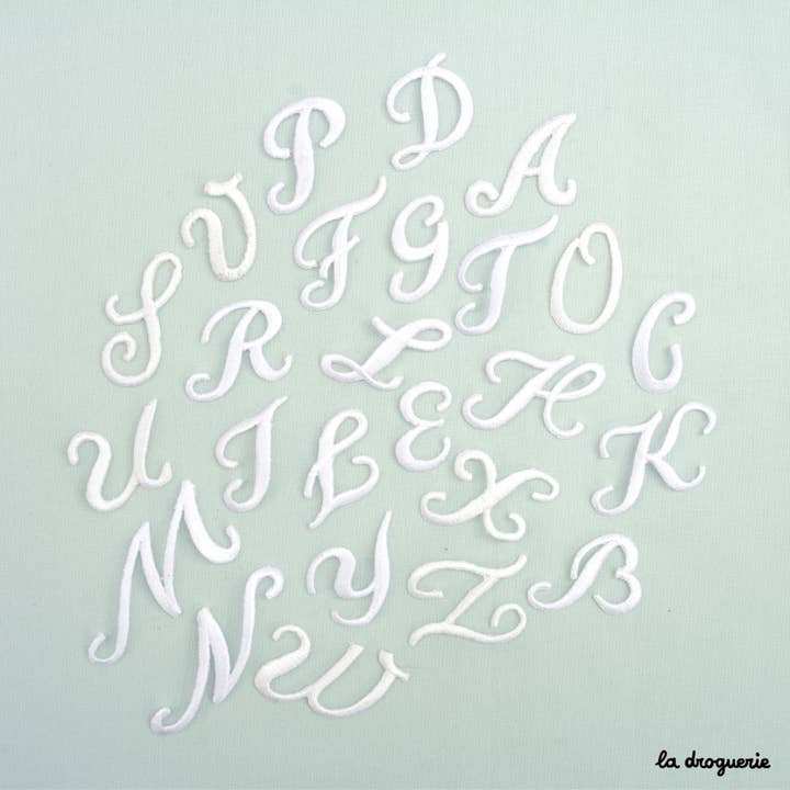 Toppa a forma di lettere dell’alfabeto bianco in stile calligrafico per la vendita all'ingrosso da parte di LA DROGUERIE