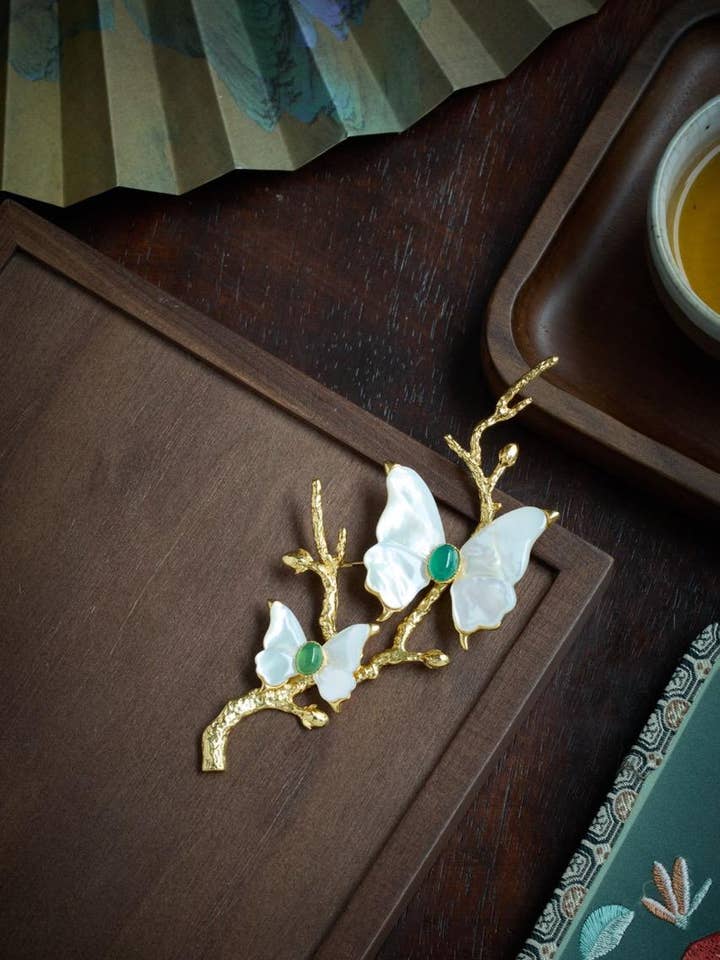 Guldbelagt sommerfuglebroche med iriserende perlemor for engroshandel hos Morado